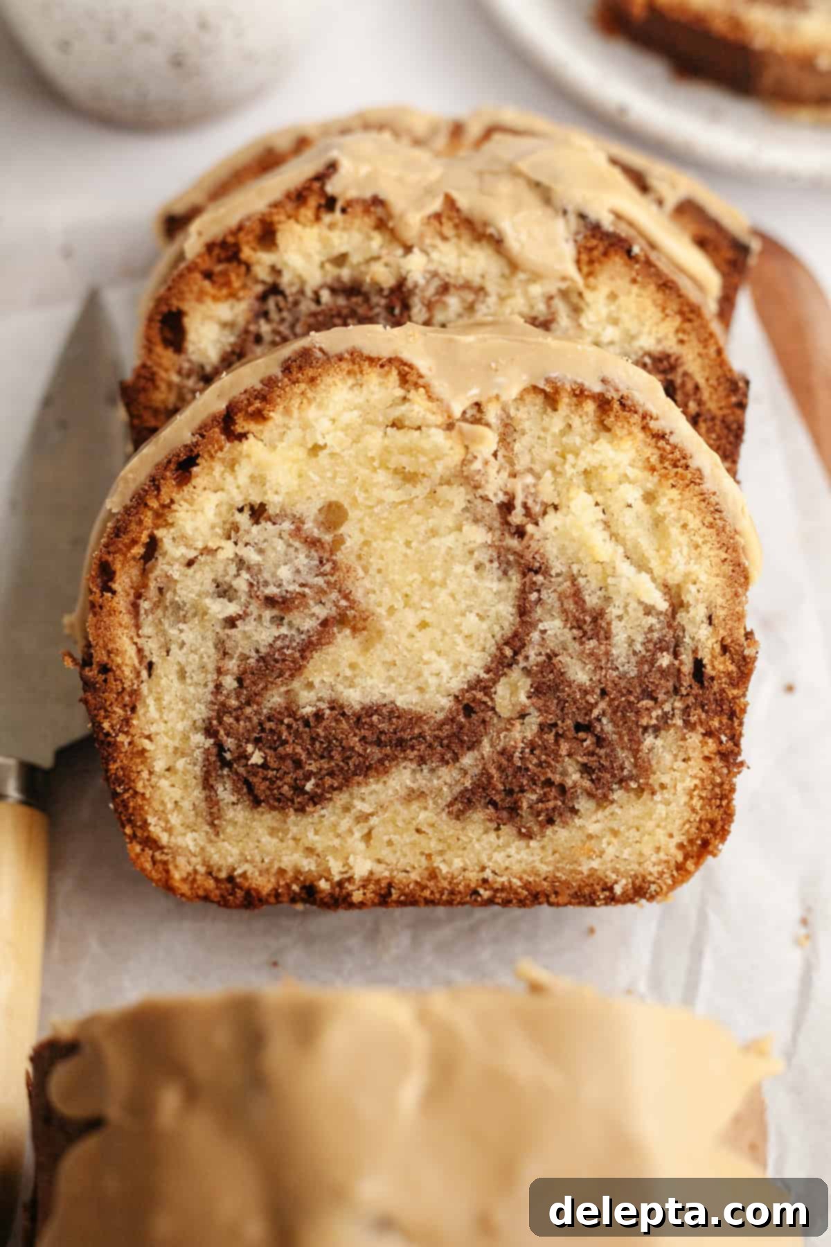 Velvet Cinnamon Pound Cake with Espresso Maple Glaze 11 Multiple slices of cinnamon loaf cake arranged artfully on parchment paper, ready to be served.