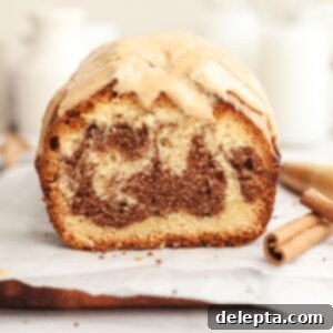 Velvet Cinnamon Pound Cake with Espresso Maple Glaze 13 A cinnamon swirl loaf cake sliced on parchment paper, featuring a beautiful spiral pattern.