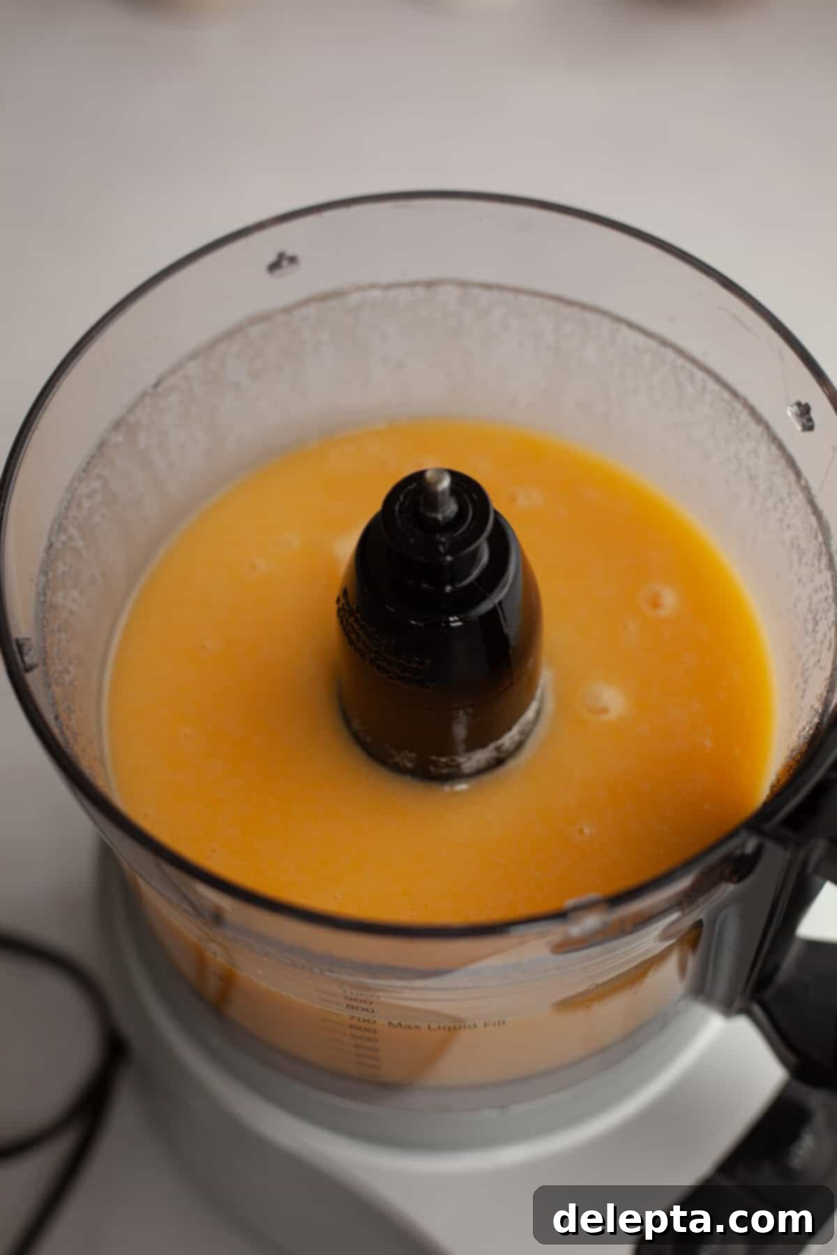 Velvet Cinnamon Pound Cake with Espresso Maple Glaze 5 A food processor containing a smooth, pale yellow batter, indicating the first step of mixing wet ingredients.