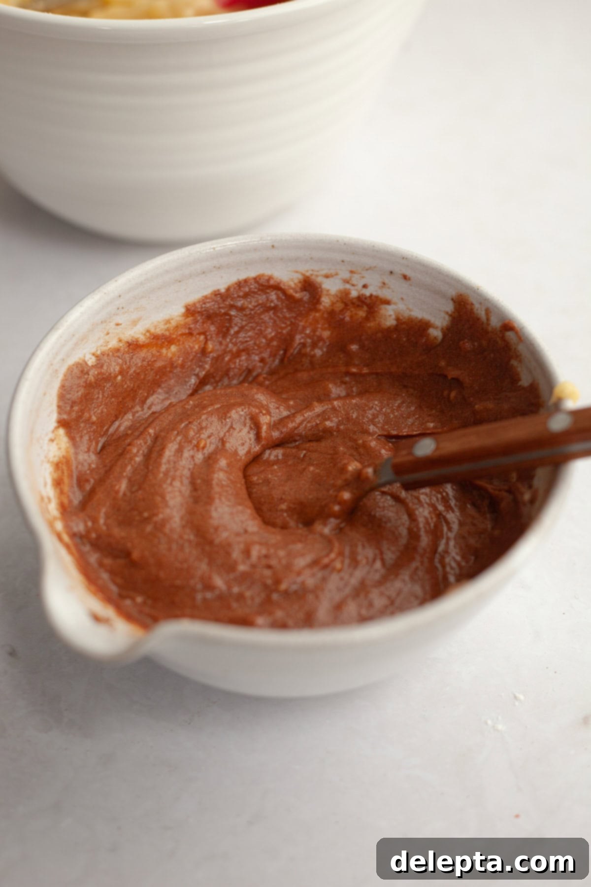 Velvet Cinnamon Pound Cake with Espresso Maple Glaze 7 Brown cake batter in a small white bowl with a spoon, representing the cinnamon swirl mixture.