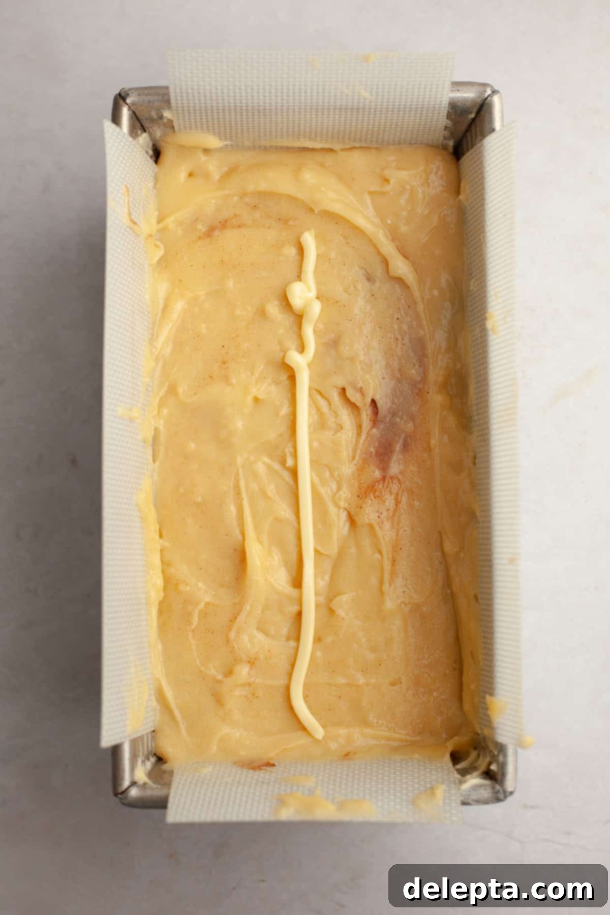 Velvet Cinnamon Pound Cake with Espresso Maple Glaze 9 A pound cake in a loaf pan, unbaked, with swirls visible and a line of butter piped down the middle.