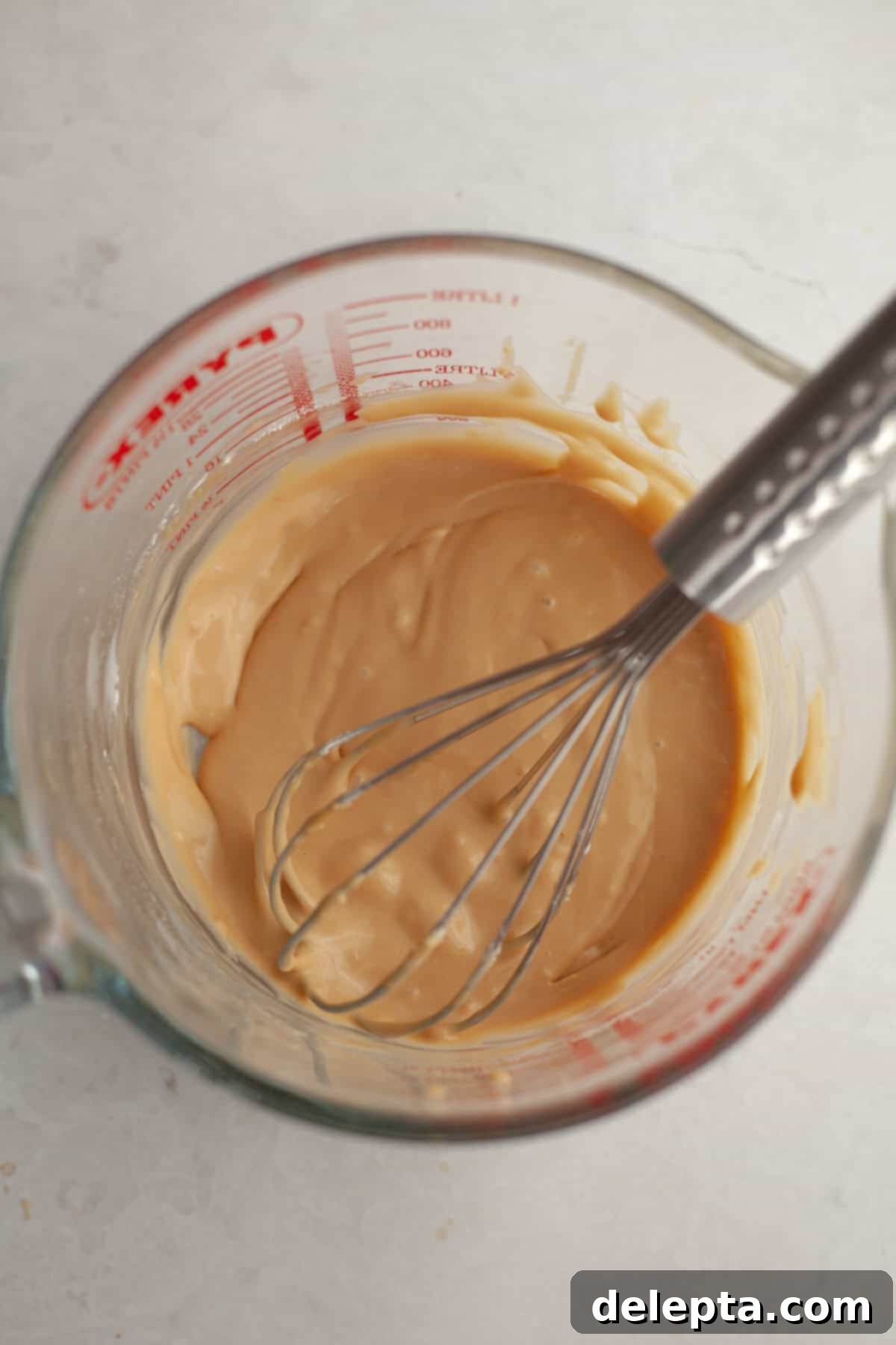 Maple Espresso Glaze 2 Maple espresso glaze in a glass jug with a whisk, ready to be drizzled.