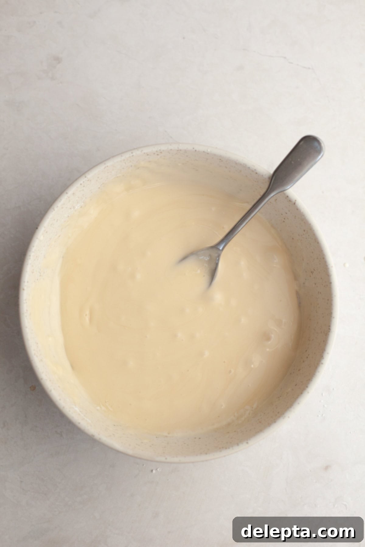 Maple Espresso Glaze 4 Maple espresso glaze in a small white bowl with a spoon, showing its smooth consistency.