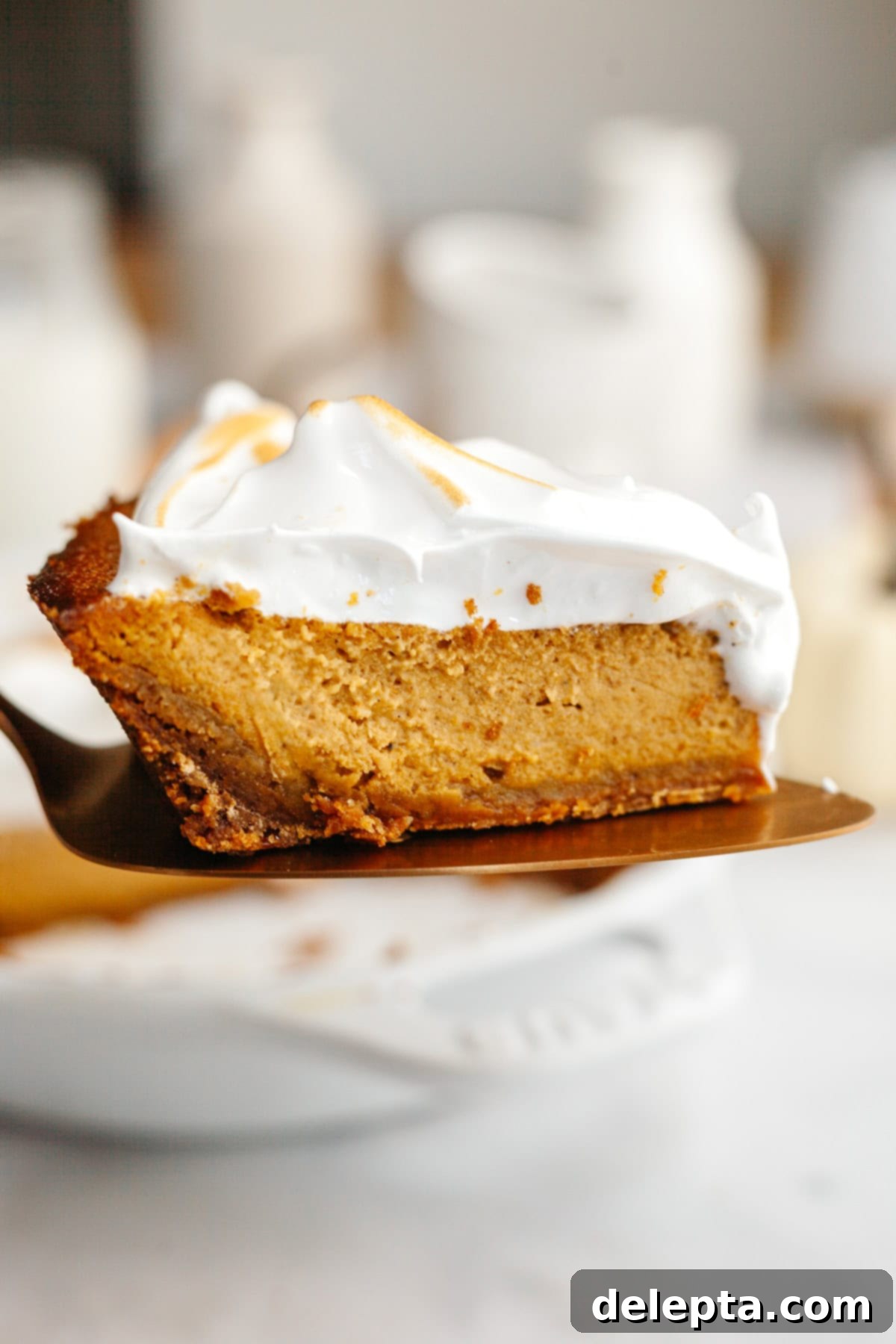 Decadent Brown Butter Pumpkin Pie with Gingersnap Perfection 12 A perfect slice of brown butter pumpkin pie with toasted marshmallow meringue resting on a cake server, ready to be served.