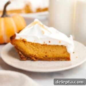 Decadent Brown Butter Pumpkin Pie with Gingersnap Perfection 13 A slice of pumpkin pie with marshmallow topping on a small plate.