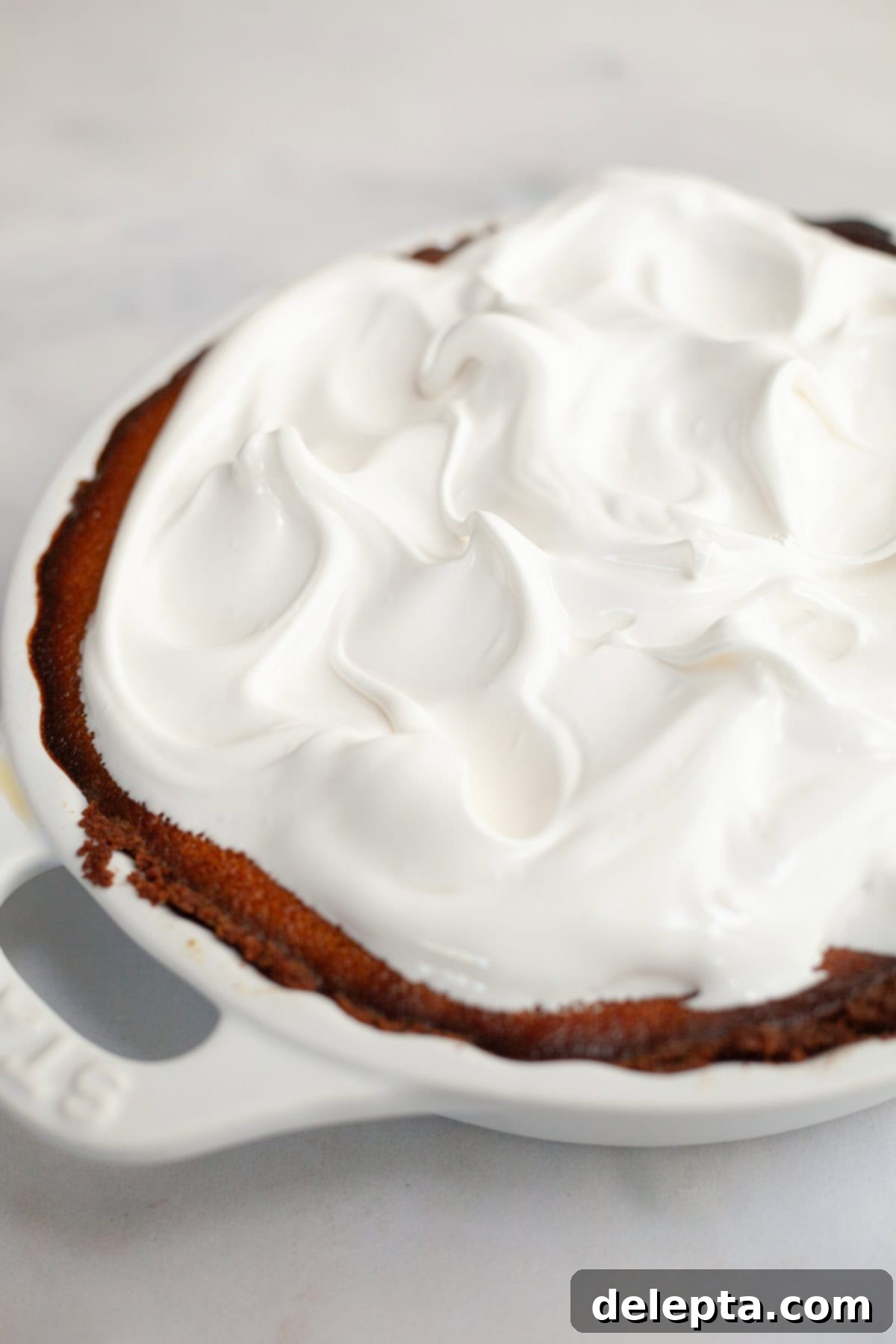 Decadent Brown Butter Pumpkin Pie with Gingersnap Perfection 10 A beautifully baked pumpkin pie generously covered in fluffy, peaked marshmallow meringue, awaiting a blowtorch to toast.