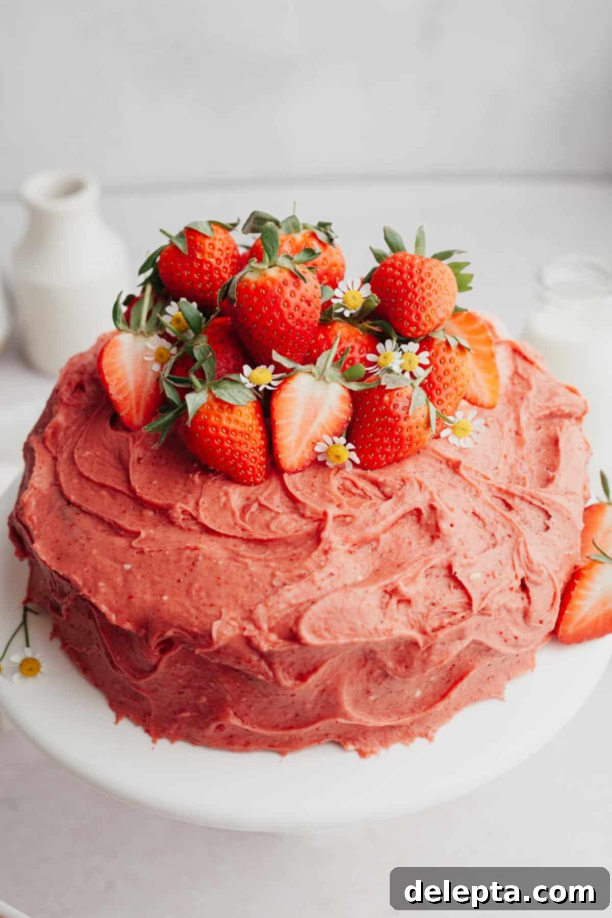 Strawberry Velvet Cake 2 A beautifully frosted strawberry cake covered in fresh whole and sliced strawberries, showcasing its natural pink hue.