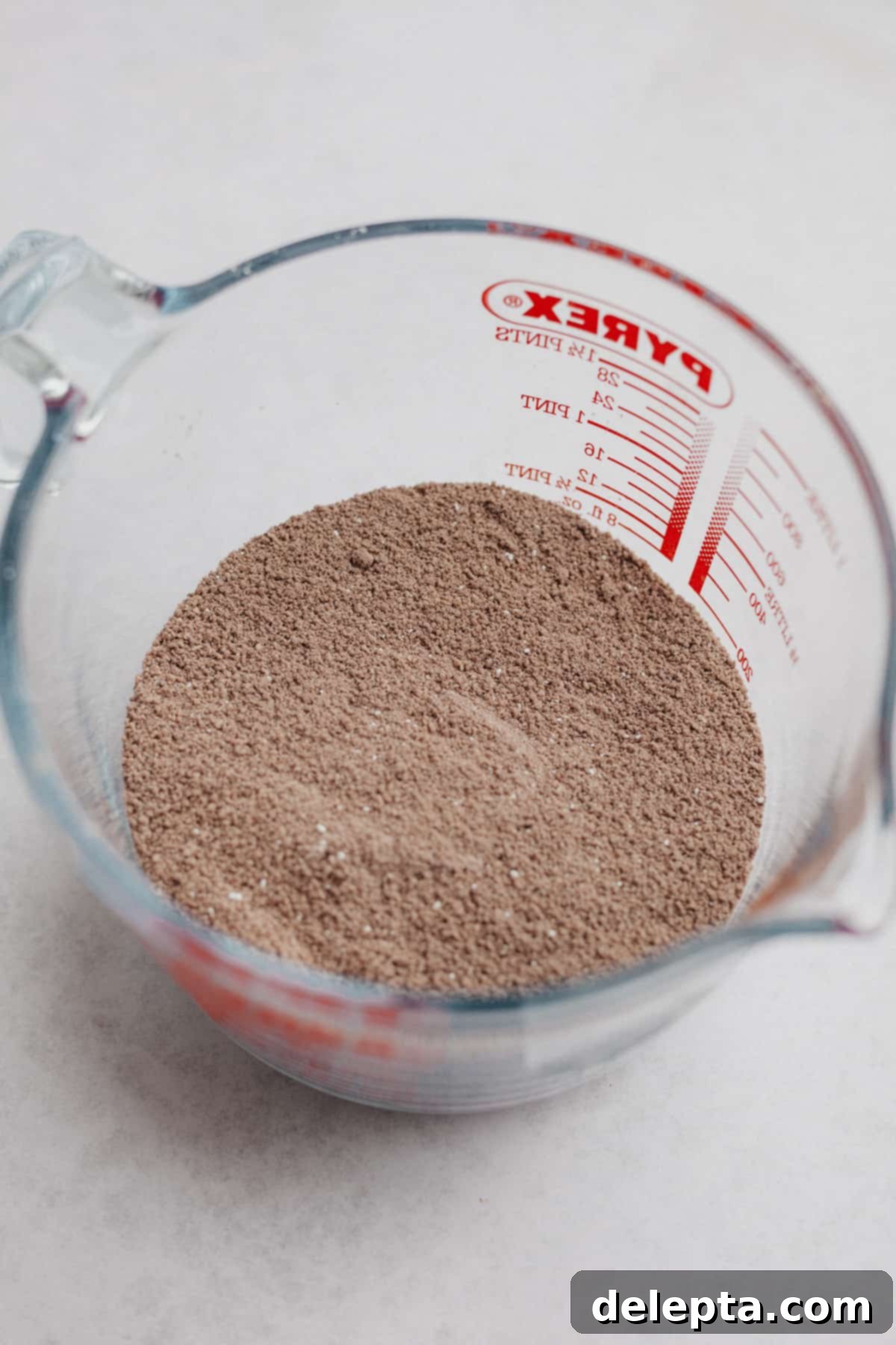 Decadent Nutella Macarons 5 A large pyrex jug containing sifted cocoa powder, almond flour, and powdered sugar