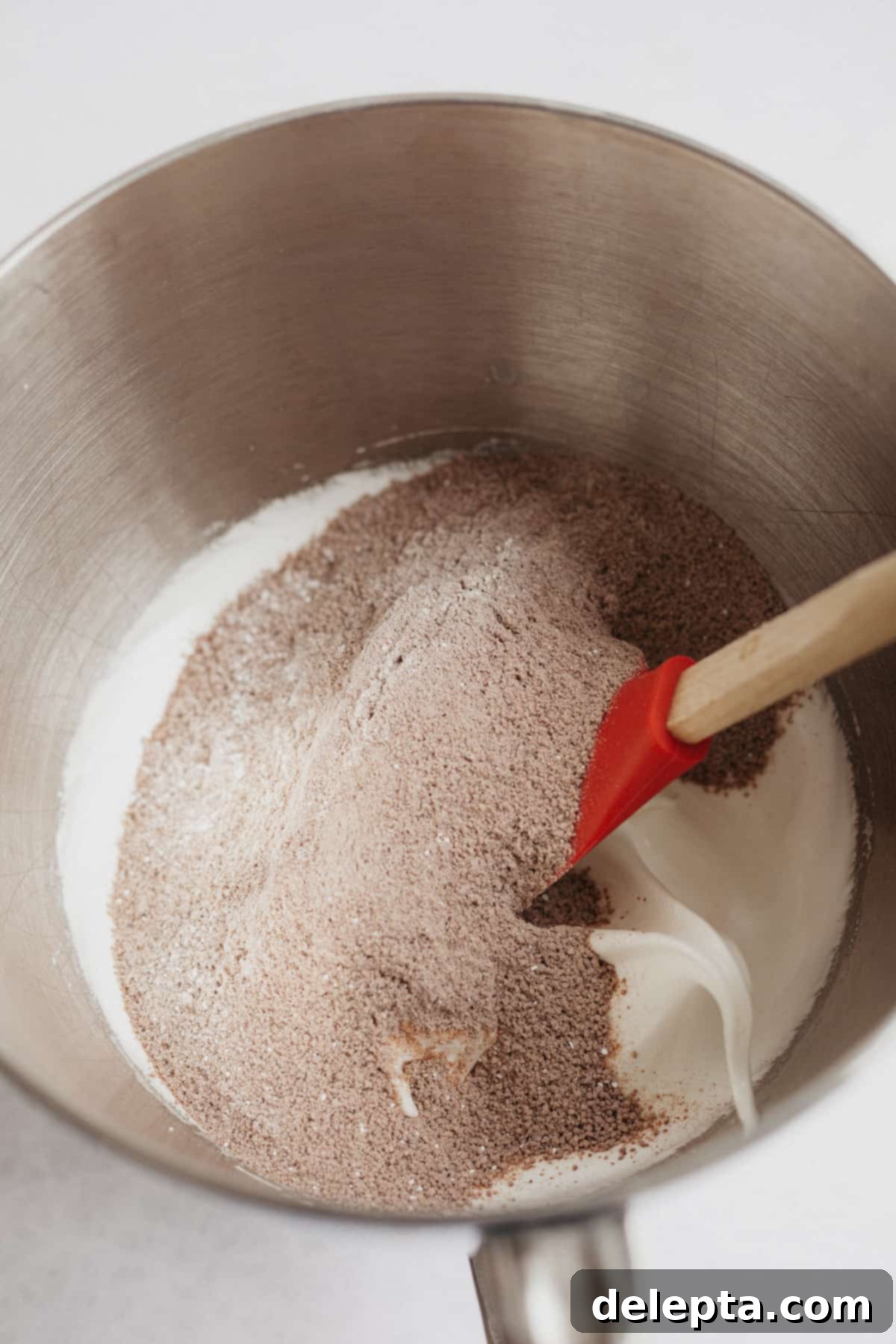 Decadent Nutella Macarons 7 A large silver mixing bowl with meringue and sifted cocoa powder, ready for folding