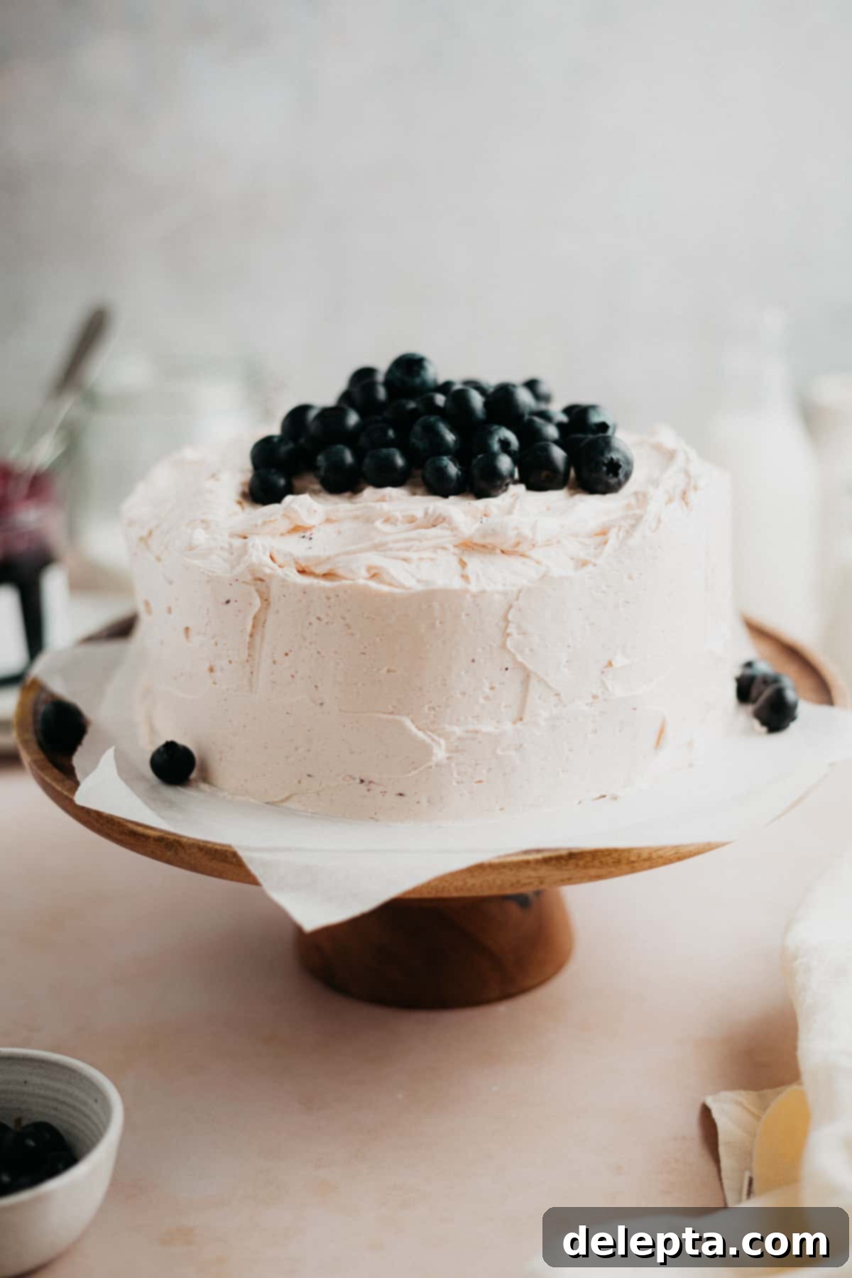 Blueberry Swirl Cake 2 A blueberry jam cake topped with blueberries on a wooden cake stand