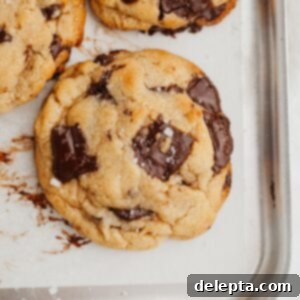 Miso Magic Brown Butter Chocolate Chip Cookies 9 A close up of a chocolate chunk cookie on parchment paper, ready to be enjoyed.