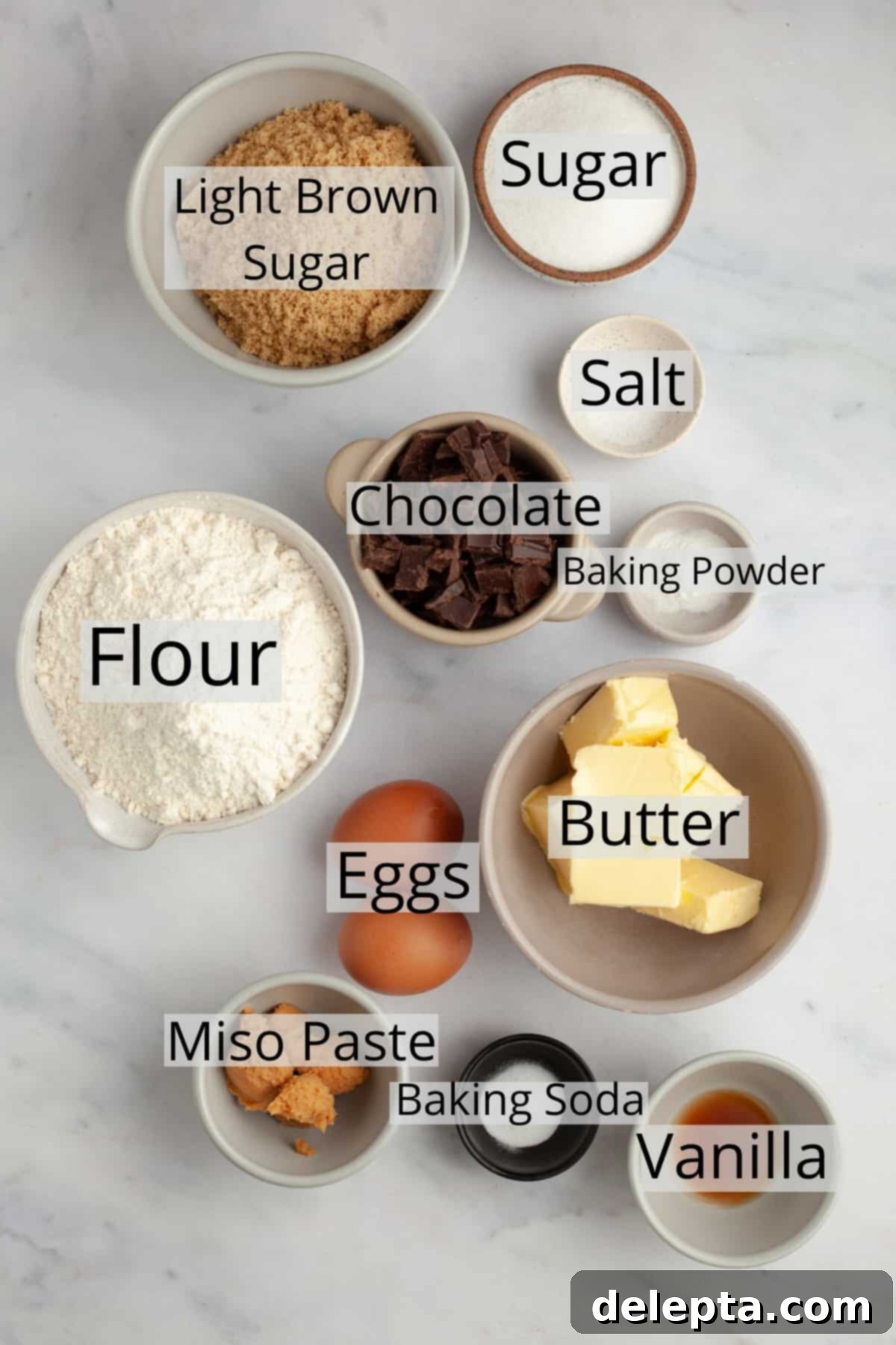 Miso Magic Brown Butter Chocolate Chip Cookies 3 All the ingredients needed to make miso chocolate chip cookies, weighed out into small bowls, including flour, butter, sugars, miso paste, eggs, and chopped chocolate.