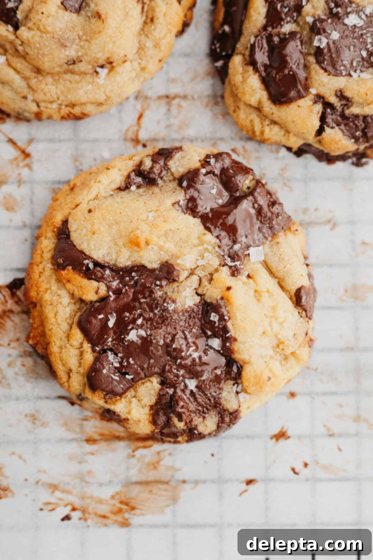 Miso Magic Brown Butter Chocolate Chip Cookies 8 A close up of a brown butter miso chocolate chunk cookie on parchment paper, highlighting its texture and melted chocolate.
