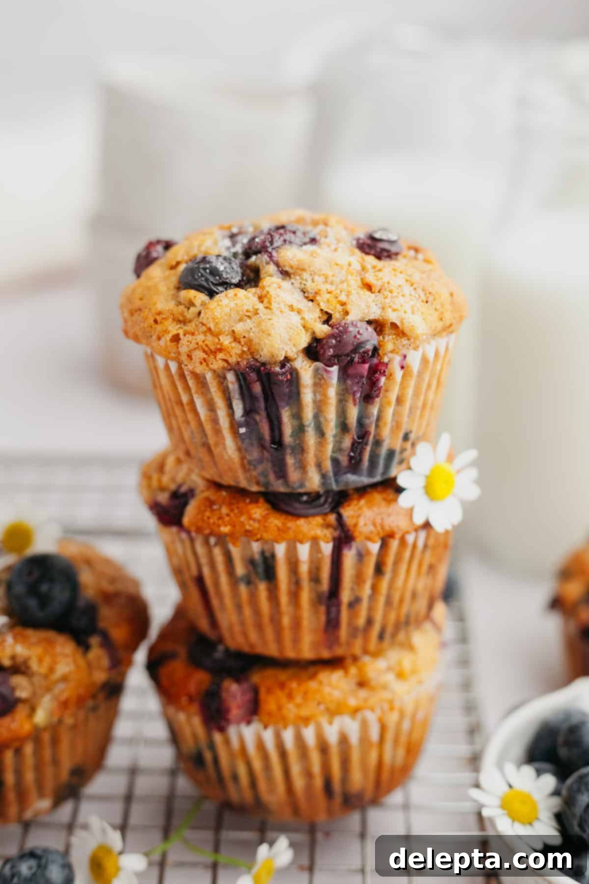 Golden Banana Berry Oatmeal Muffins 2 A stack of three blueberry muffins, golden brown with visible blueberries and oats.