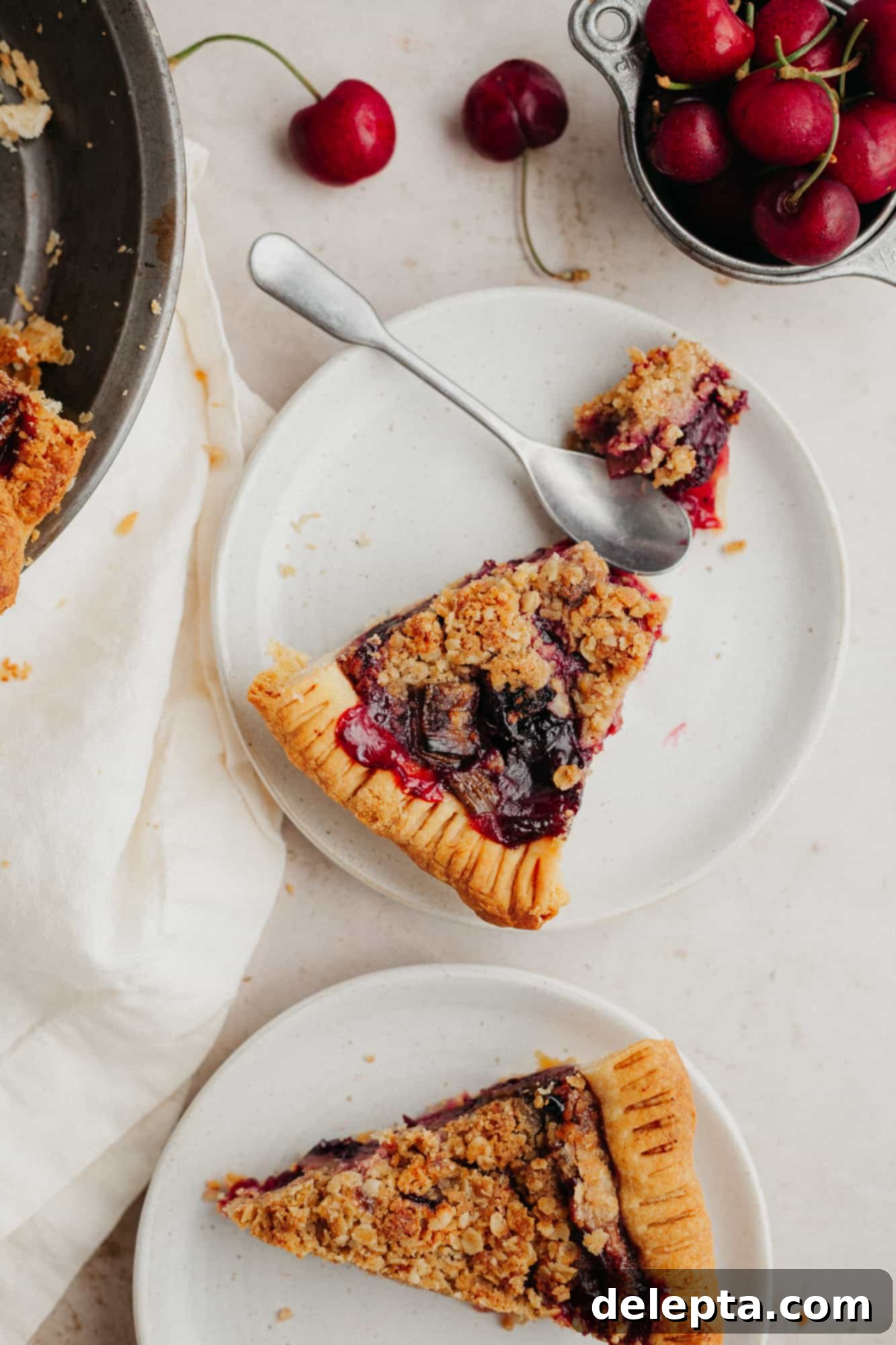 Homestyle Cherry Rhubarb Pie 2 Two slices of cherry rhubarb crumb pie on a small beige plate