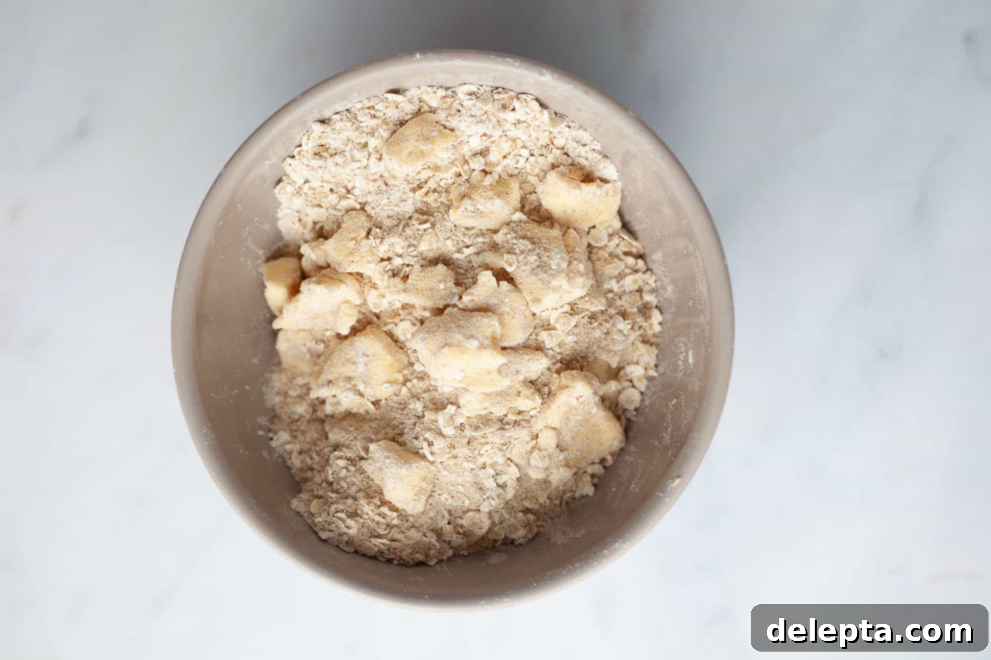 Homestyle Cherry Rhubarb Pie 11 A small beige bowl with what looks like flour, oats, and small bits of butter