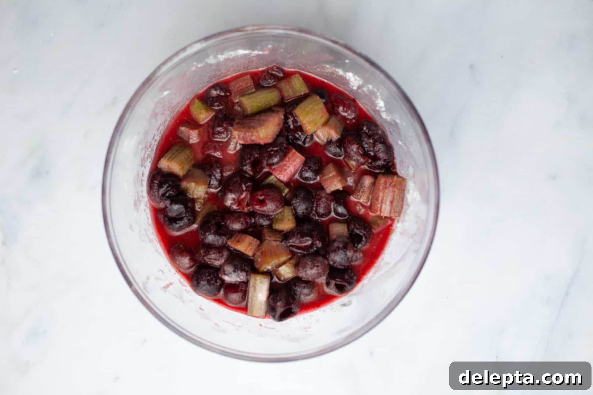 Homestyle Cherry Rhubarb Pie 12 A pyrex mixing bowl with cherries, cut rhubarb and their juice