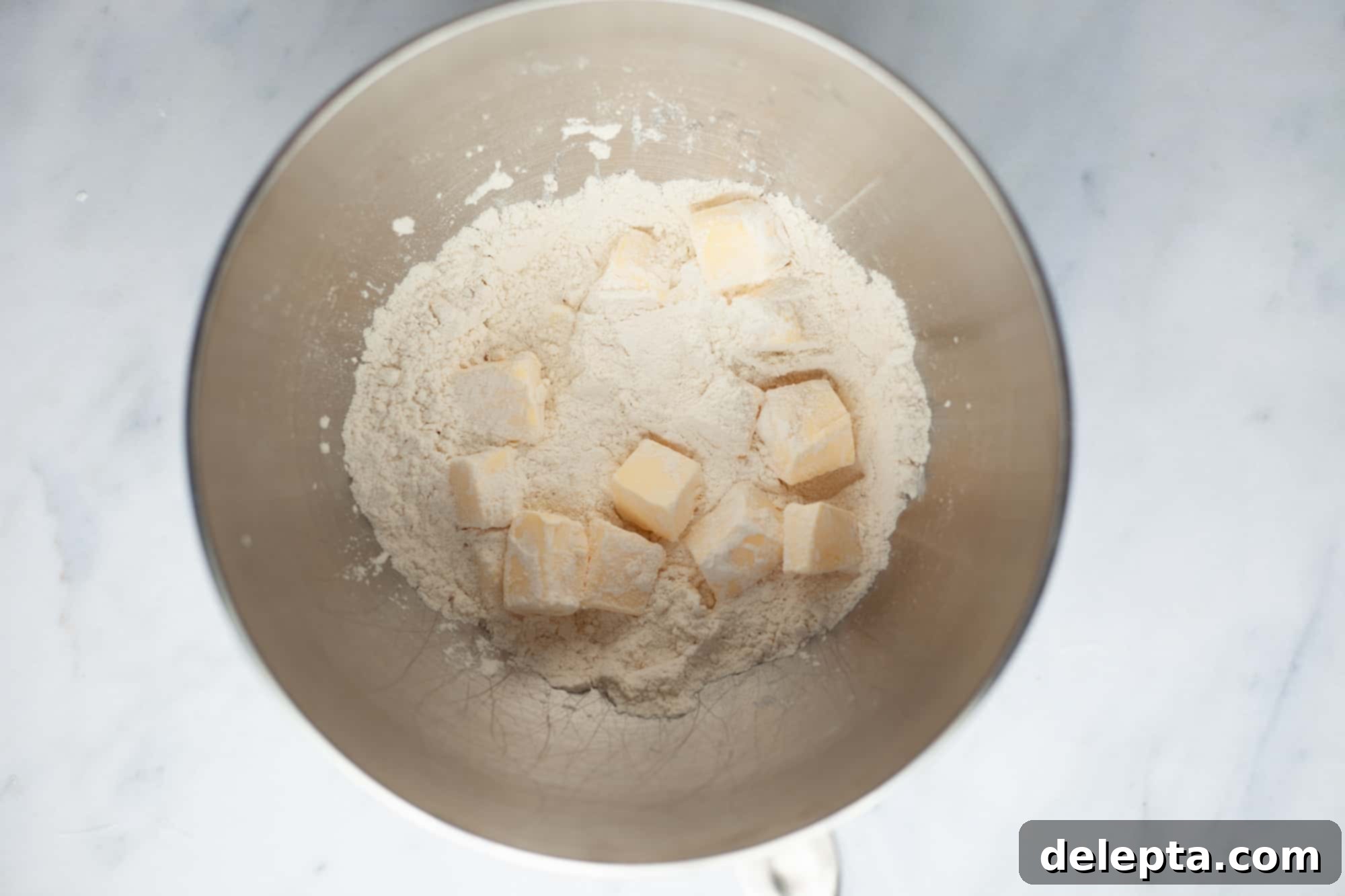 Homestyle Cherry Rhubarb Pie 5 A silver bowl with flour and cut pieces of butter
