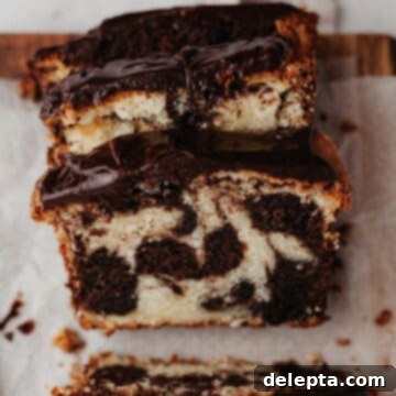 Elegant Swirl Loaf 9 Three slices of a moist marble loaf cake with a glossy chocolate ganache on top, perfectly arranged for serving.