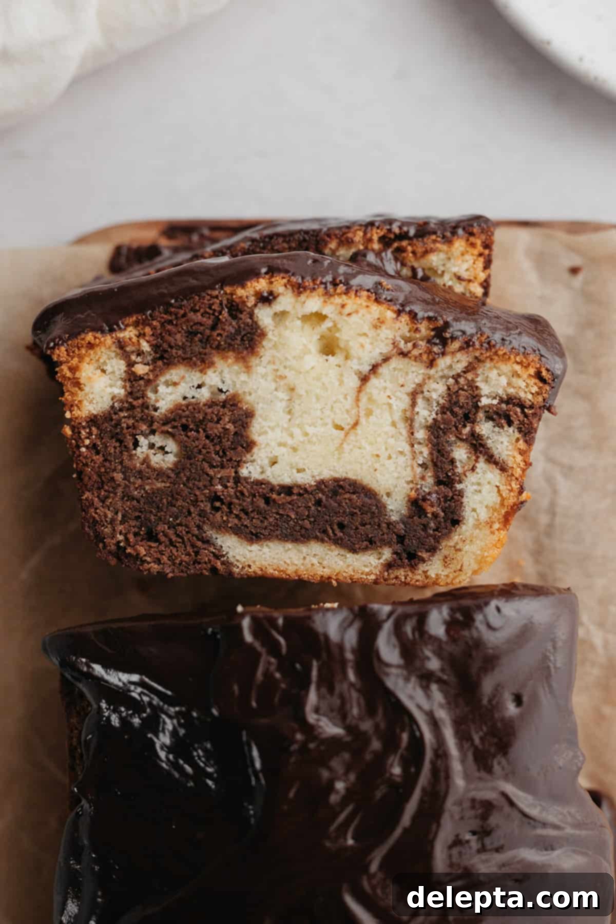 Elegant Swirl Loaf 7 An overhead shot of a freshly baked slice of marble loaf cake, showing the beautiful swirls and ganache.