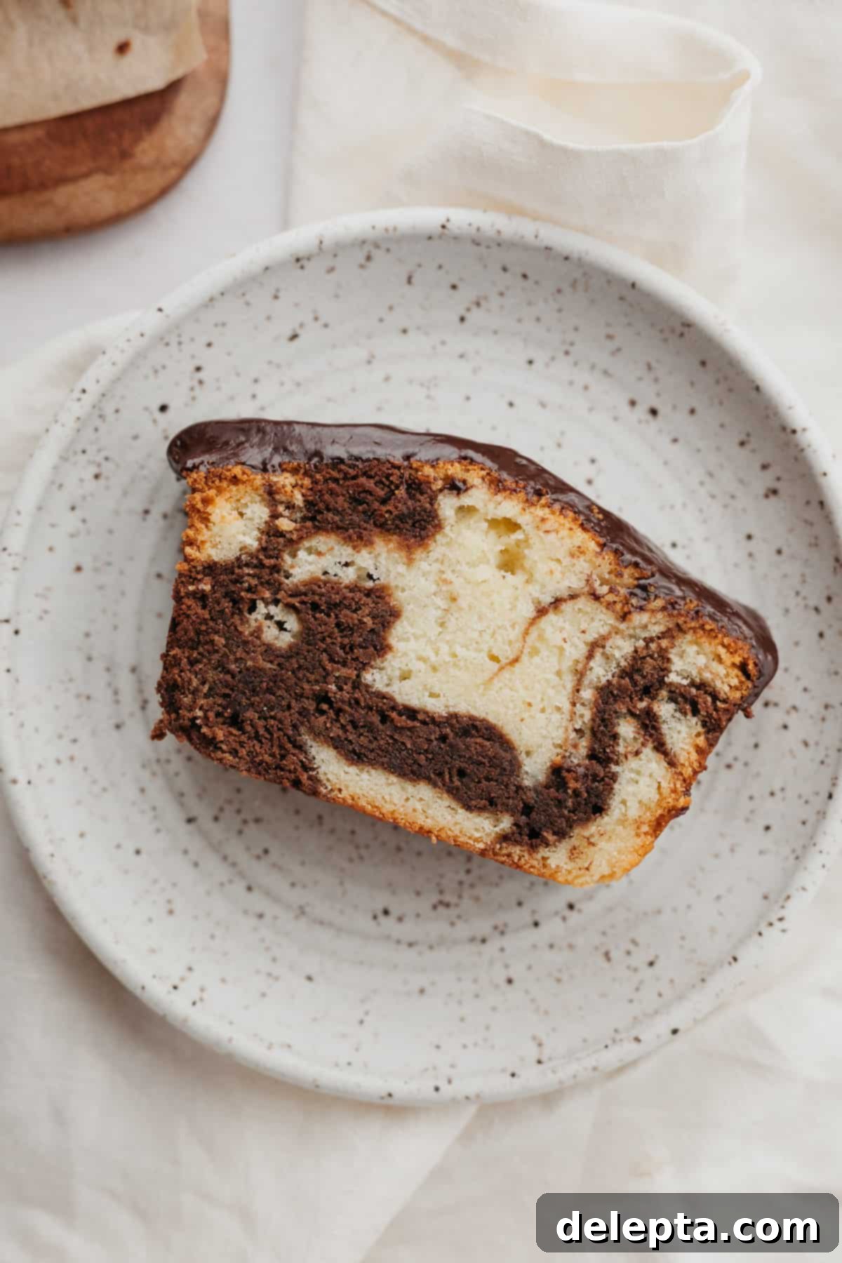 Elegant Swirl Loaf 8 A beautifully sliced marble loaf cake on a small white plate, ready to be enjoyed, showcasing the perfect swirl.