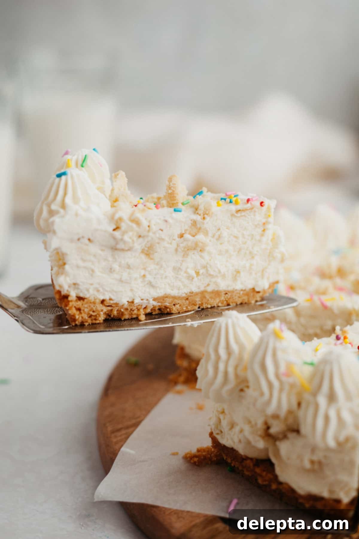 Blonde Oreo Cheesecake 2 A vibrant slice of no-bake Golden Oreo cheesecake, adorned with rainbow sprinkles, being carefully lifted from the whole dessert.