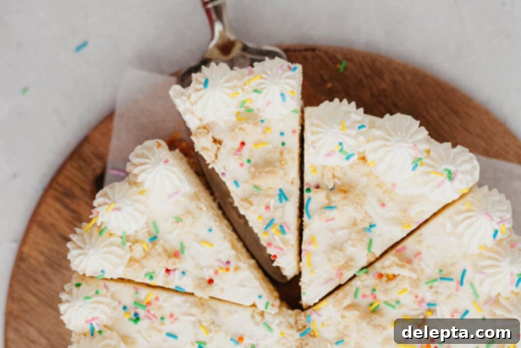 Blonde Oreo Cheesecake 11 An overhead view of a beautifully decorated Golden Oreo cheesecake with three slices already cut, showcasing the vibrant rainbow sprinkles.