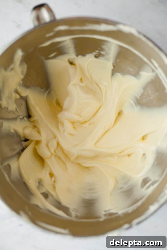 Blonde Oreo Cheesecake 7 A silver mixing bowl containing smooth, creamy, and lump-free cream cheese after being beaten.