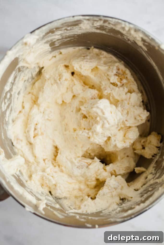 Blonde Oreo Cheesecake 9 A silver mixing bowl with creamy cheesecake batter, now perfectly blended with chunky crushed Golden Oreos.
