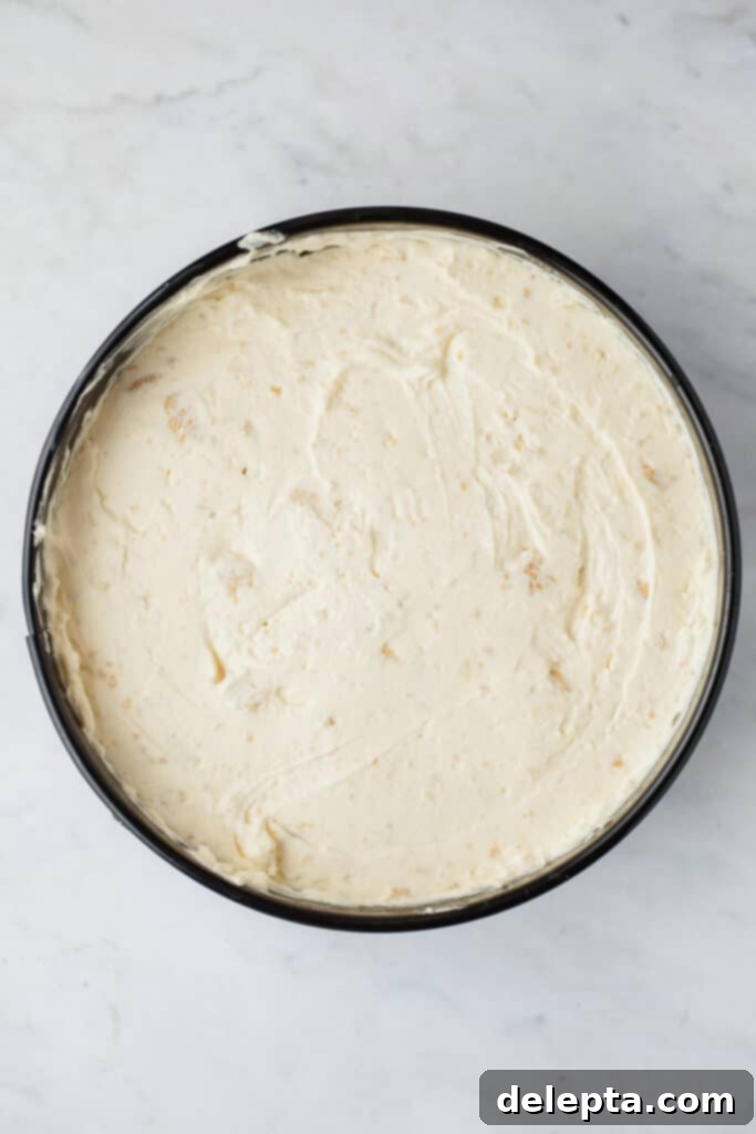 Blonde Oreo Cheesecake 10 An overhead shot of a springform pan filled to the brim with smooth, creamy no-bake cheesecake batter.