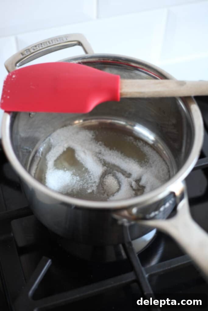 Sea Salt Caramel Macarons 11 A small silver saucepan on a stove with melting sugar, slowly transforming into caramel.