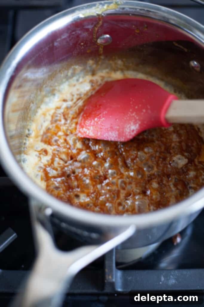 Sea Salt Caramel Macarons 13 Close-up of caramel bubbling vigorously in a small saucepan as butter is added, creating a rich, frothy mixture.