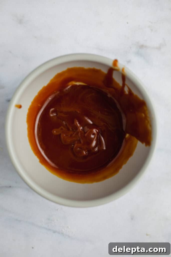 Sea Salt Caramel Macarons 14 Homemade salted caramel sauce cooling in a grey ceramic bowl, showing its thick and glossy texture.