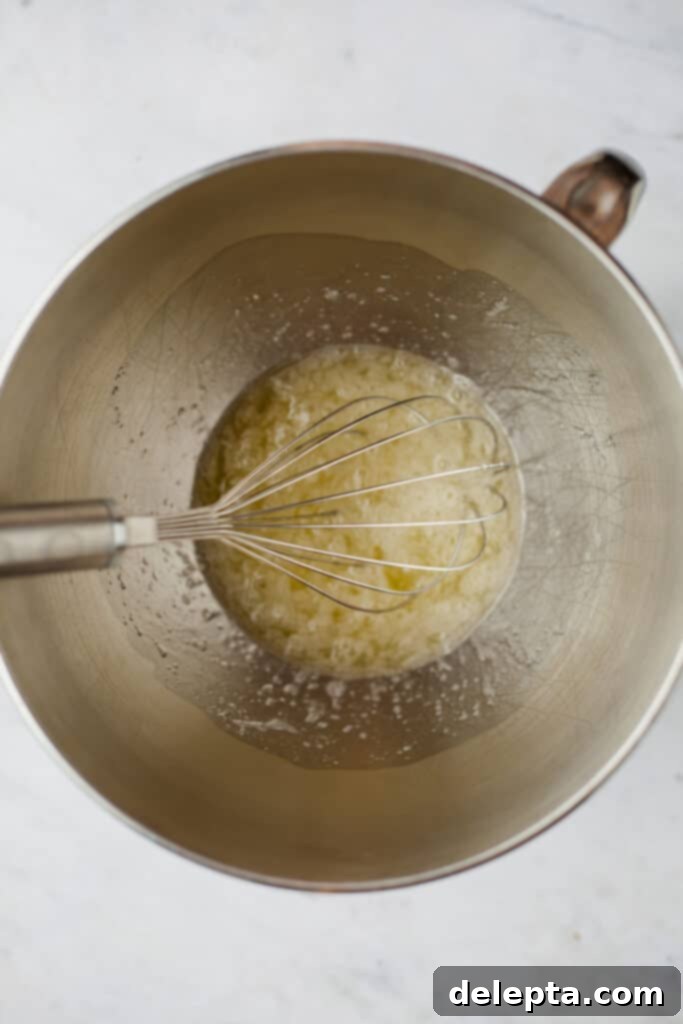 Sea Salt Caramel Macarons 5 A silver mixing bowl containing egg whites and sugar being whisked over a simmering water bath (double boiler) for Swiss meringue.