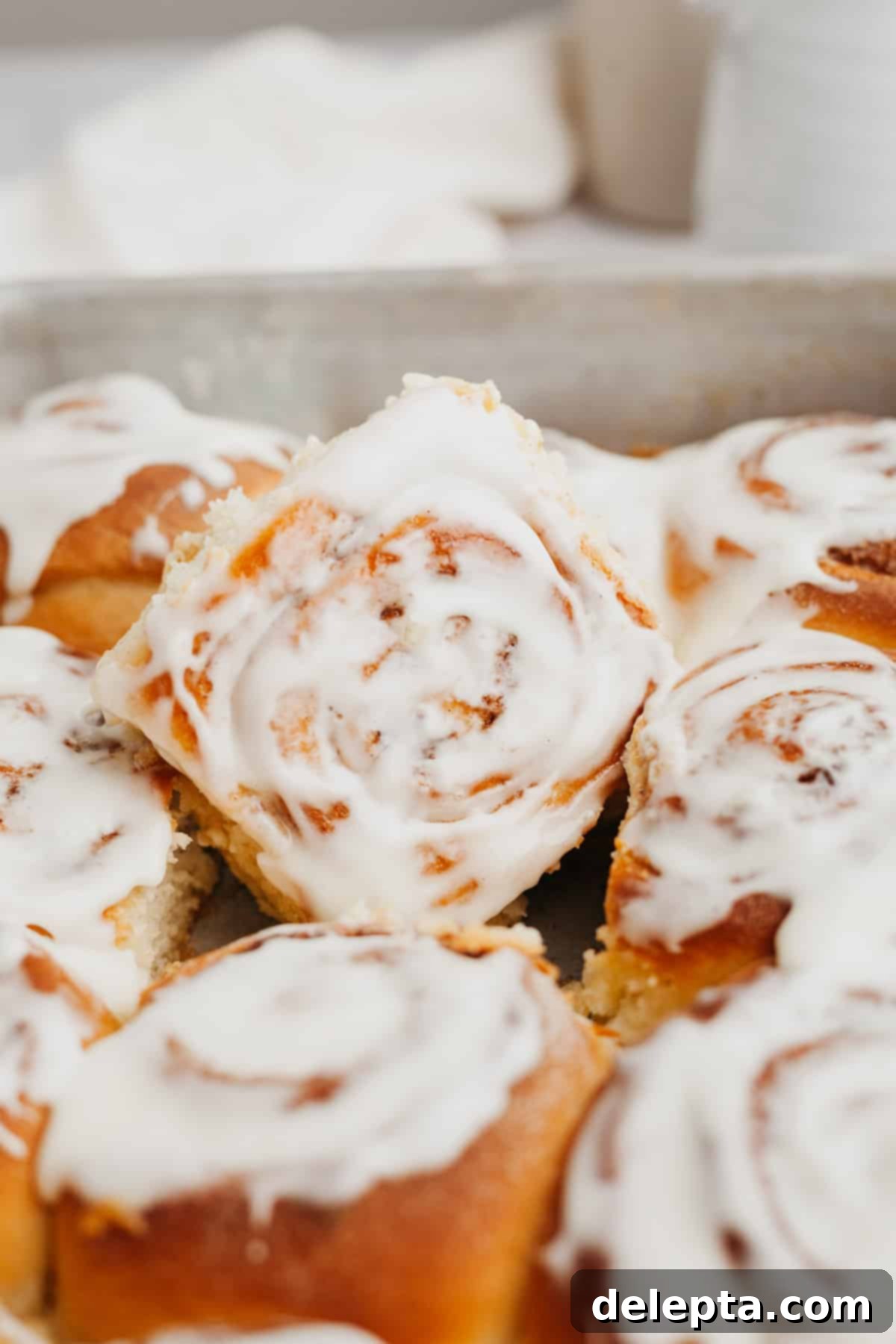 Decadent Brioche Cinnamon Rolls with Heavy Cream 8 Close-up of baked brioche cinnamon rolls covered in a thick layer of cream cheese glaze, ready to be served.