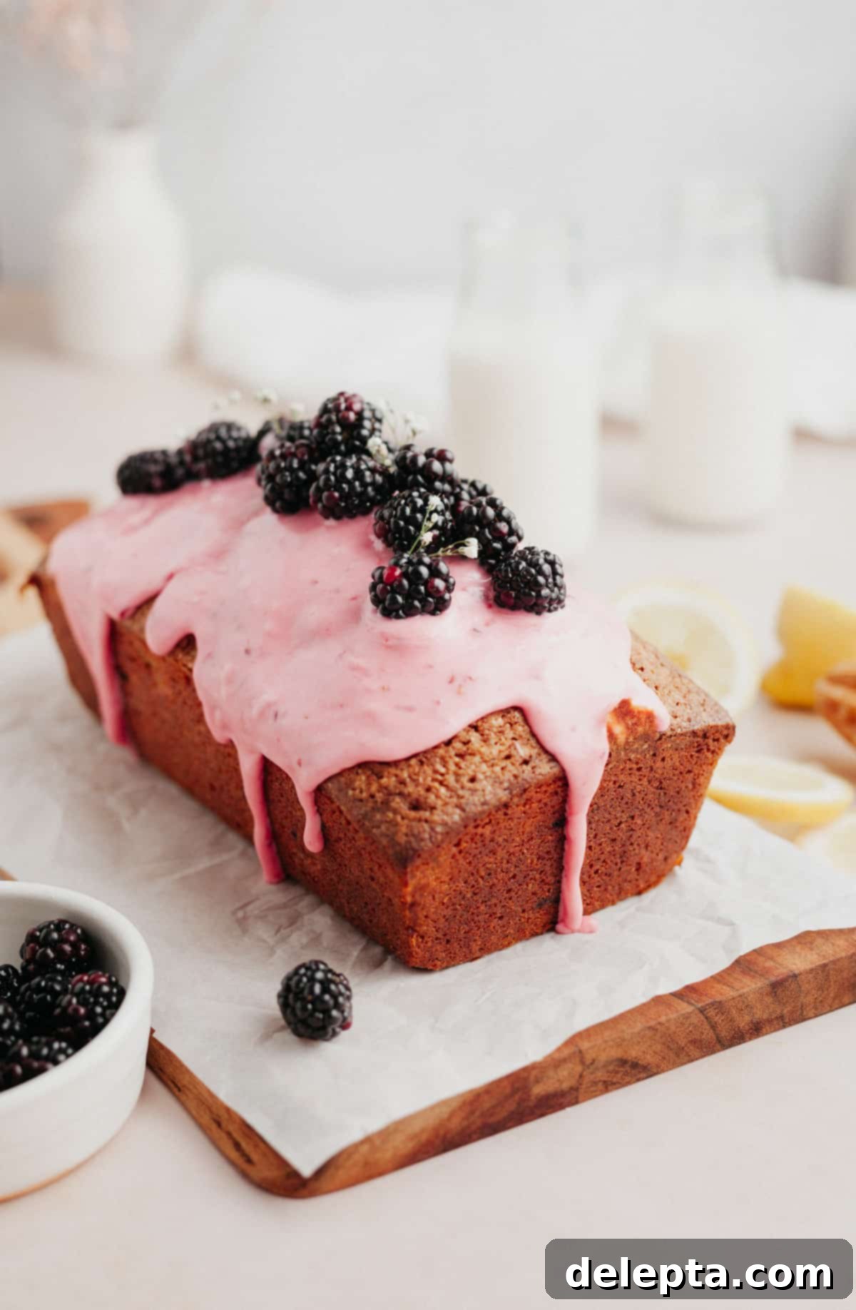 Vibrant Blackberry Lemon Loaf 7 A beautifully glazed blackberry lemon loaf cake on parchment paper, garnished with fresh blackberries.