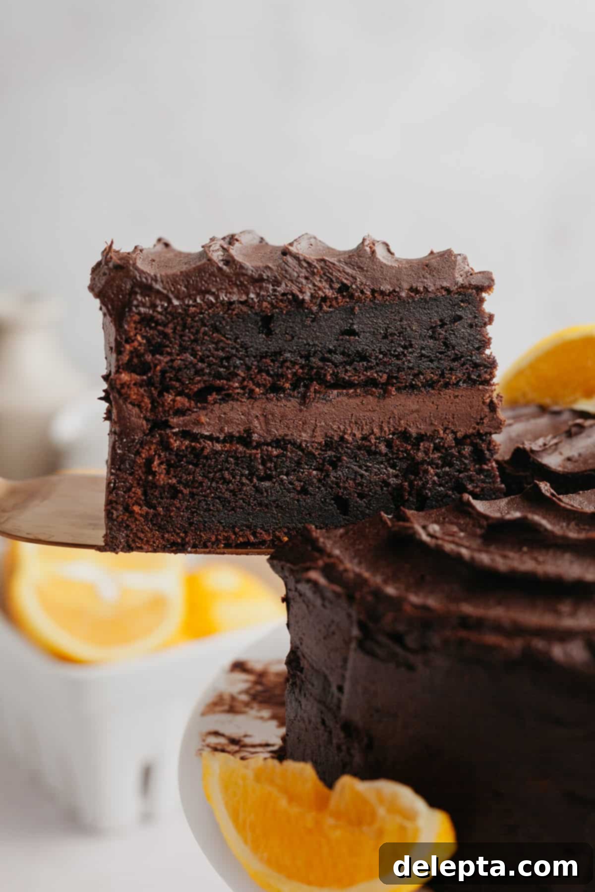 Zesty Chocolate Orange Cake 2 A slice of chocolate cake being lifted out, showcasing moist layers and creamy orange-infused chocolate frosting.