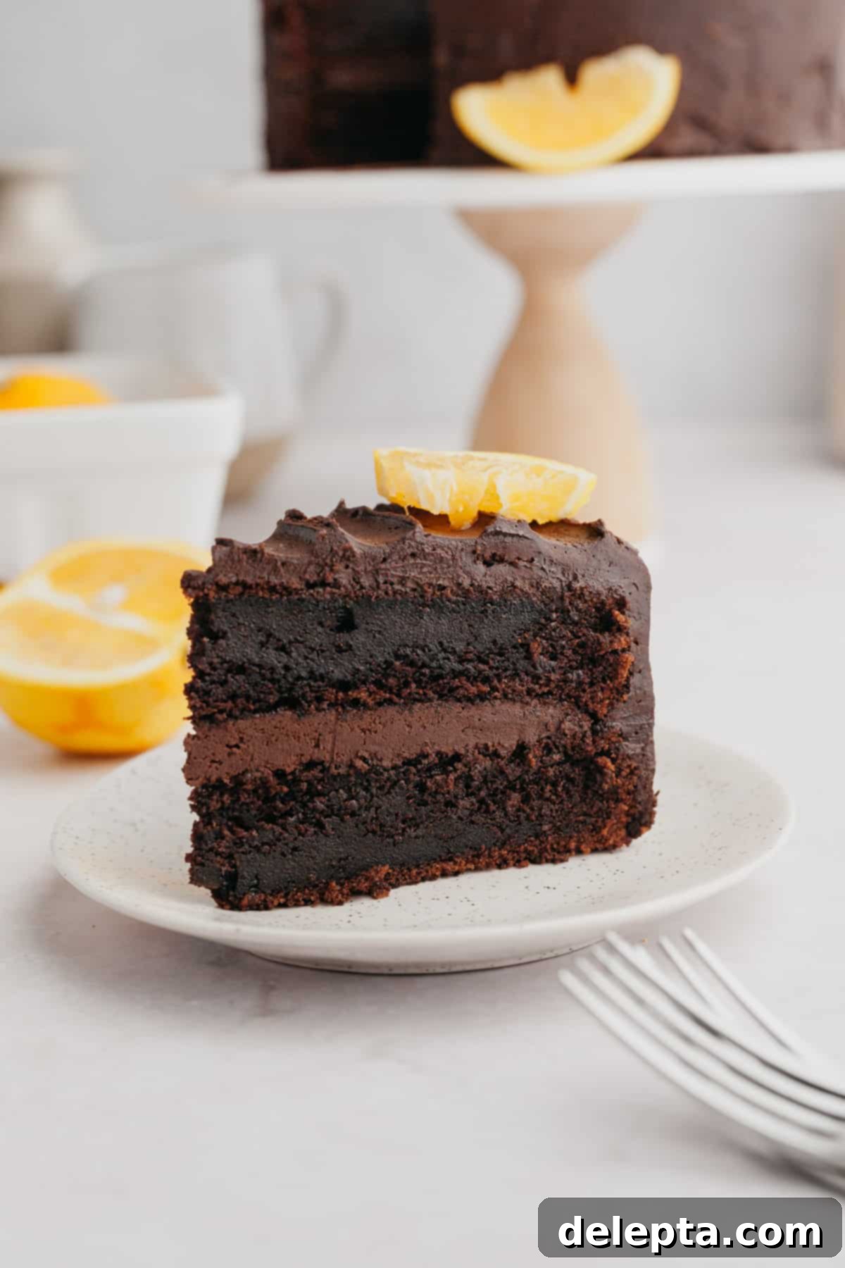 Zesty Chocolate Orange Cake 9 A delectable slice of chocolate orange cake on a small white plate, ready to be enjoyed.