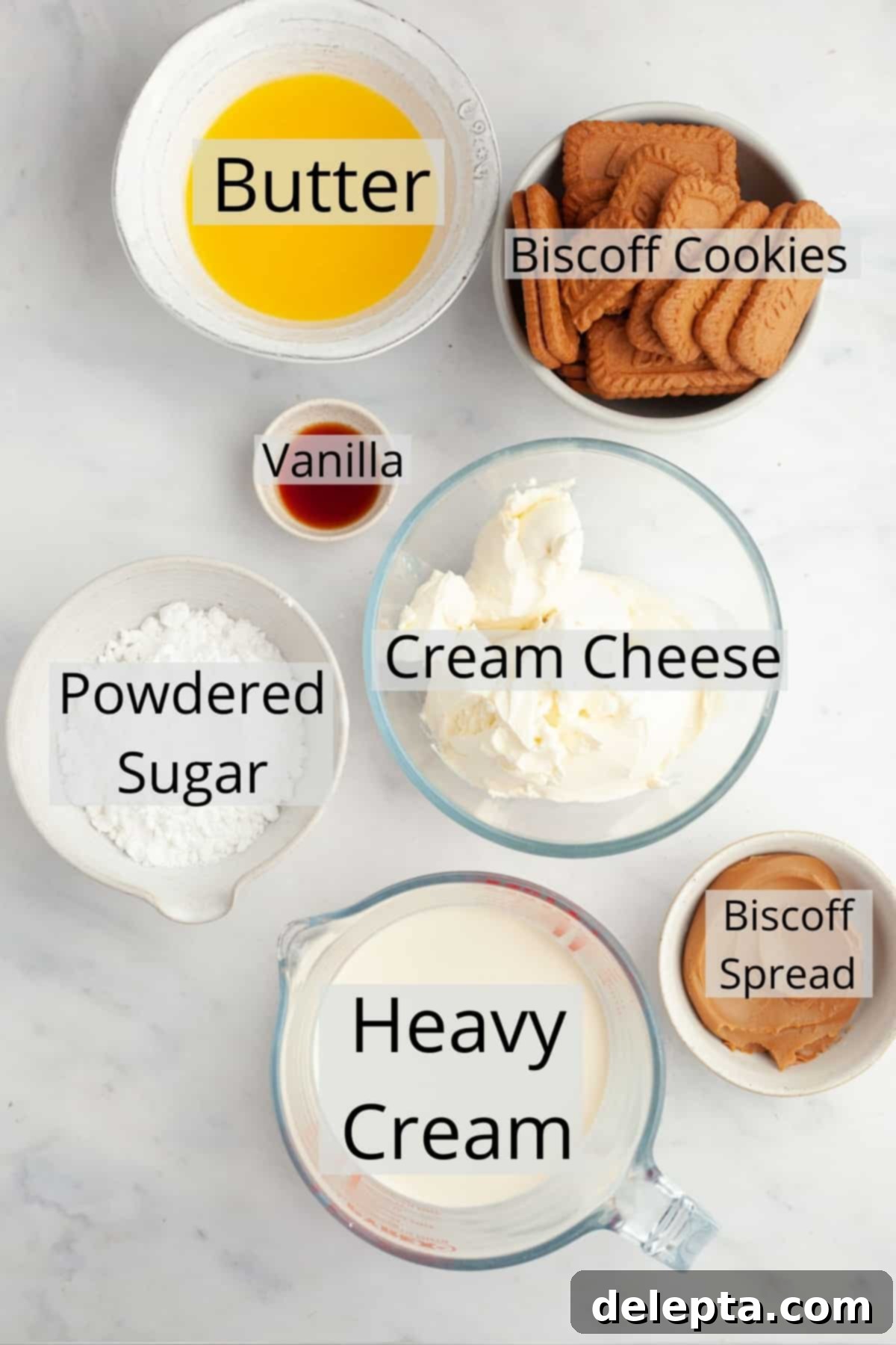 Simple No-Bake Lotus Biscoff Cheesecake 3 Ingredients needed for Biscoff cheesecake, weighed out into small bowls, including cream cheese, Biscoff spread, and crushed cookies.