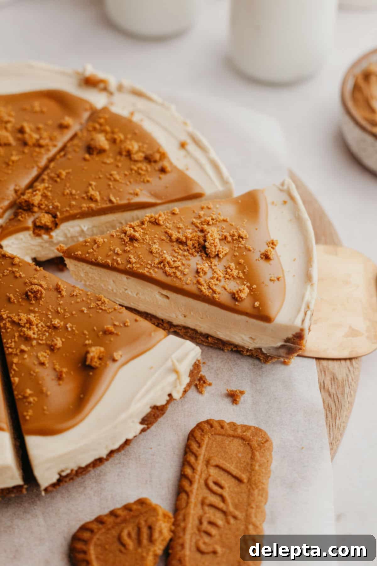 Simple No-Bake Lotus Biscoff Cheesecake 8 A perfectly cut slice of Biscoff cheesecake on a gold cake server, showcasing its layers.
