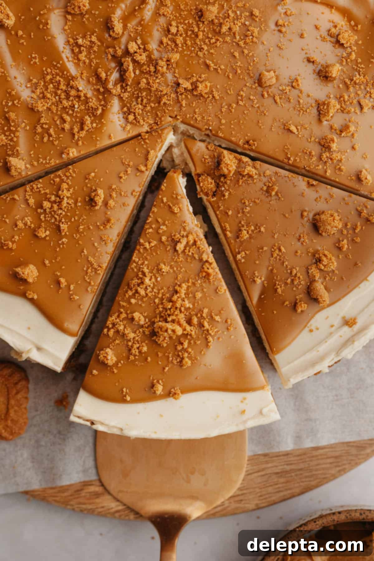 Simple No-Bake Lotus Biscoff Cheesecake 9 A Biscoff cheesecake with three slices cut, showcasing the rich topping and creamy layers.
