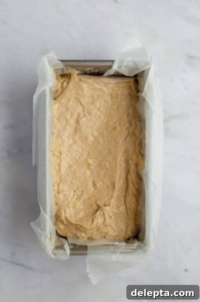 Cinnamon Crumble Banana Bread 13 Unbaked banana bread batter poured into a parchment-lined loaf pan, ready for the topping