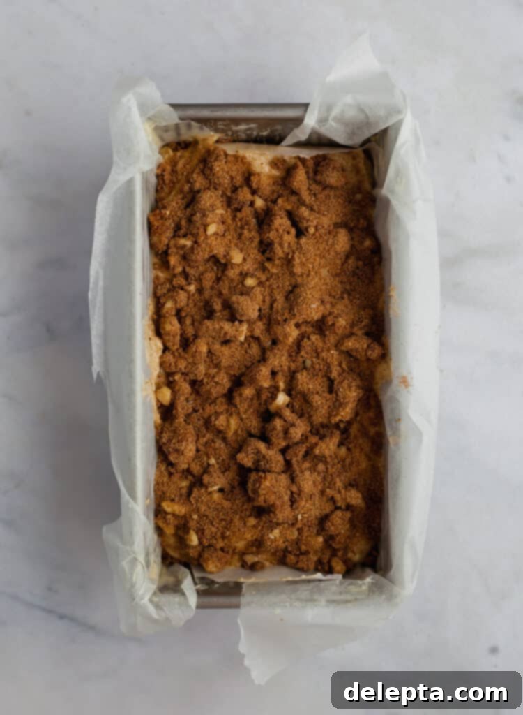 Cinnamon Crumble Banana Bread 14 Unbaked banana bread in a loaf pan covered with a generous layer of cinnamon crunch topping, ready for the oven