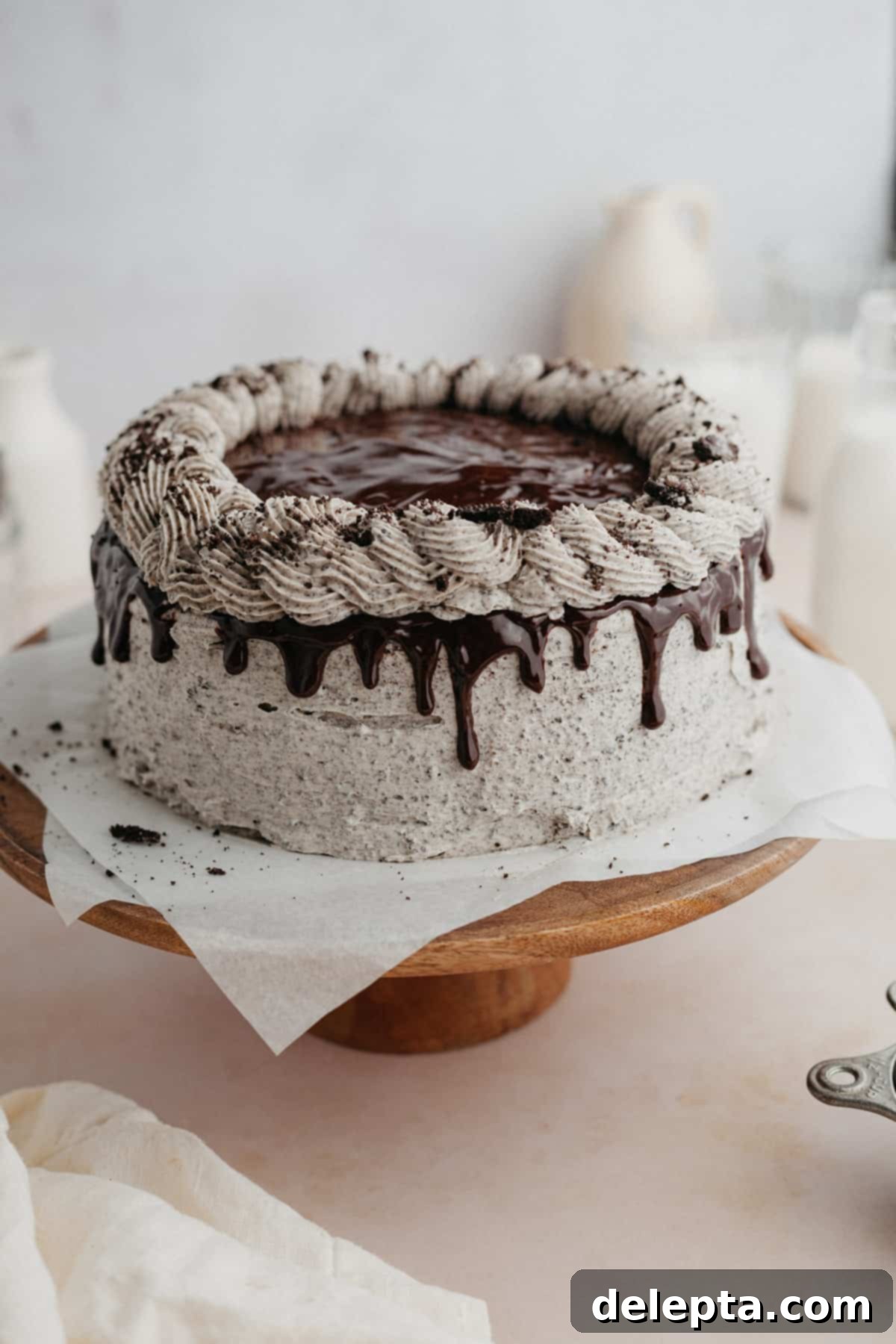 Decadent Oreo Drip Cake 2 An Oreo drip cake on a wooden cake stand, beautifully decorated with chocolate ganache and cookie crumbs