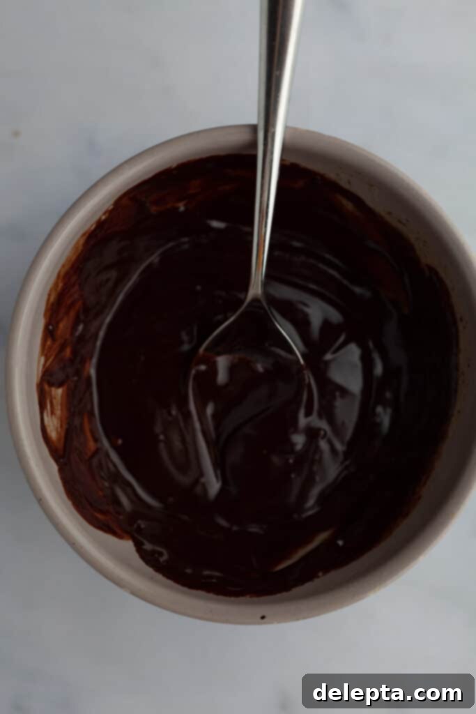 Decadent Oreo Drip Cake 14 Smooth chocolate ganache in a grey bowl, perfectly melted and ready for use