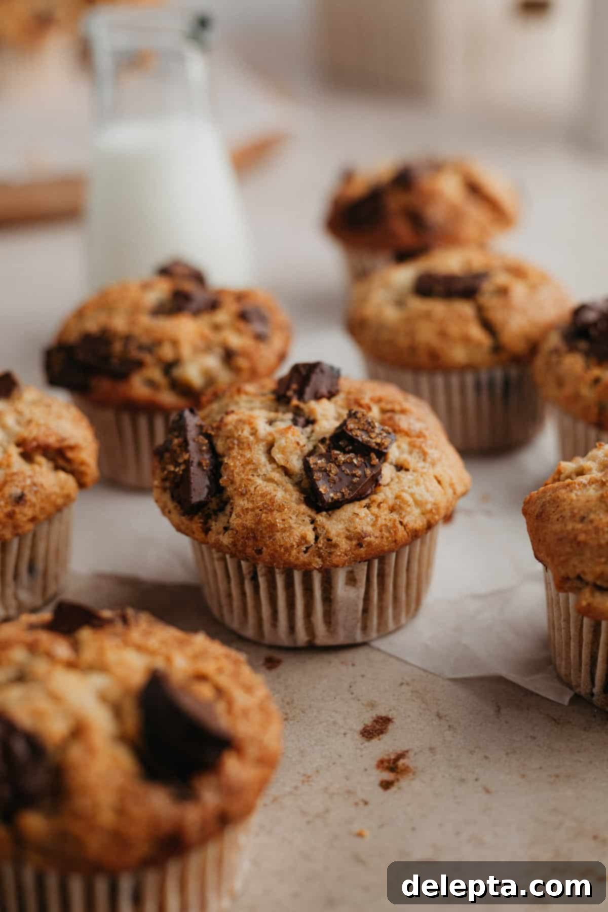 Irresistible Chocolate Chip Peanut Butter Muffins 2 Close-up of fluffy peanut butter banana oat muffins with visible chocolate chunks on parchment paper, ready to be enjoyed.