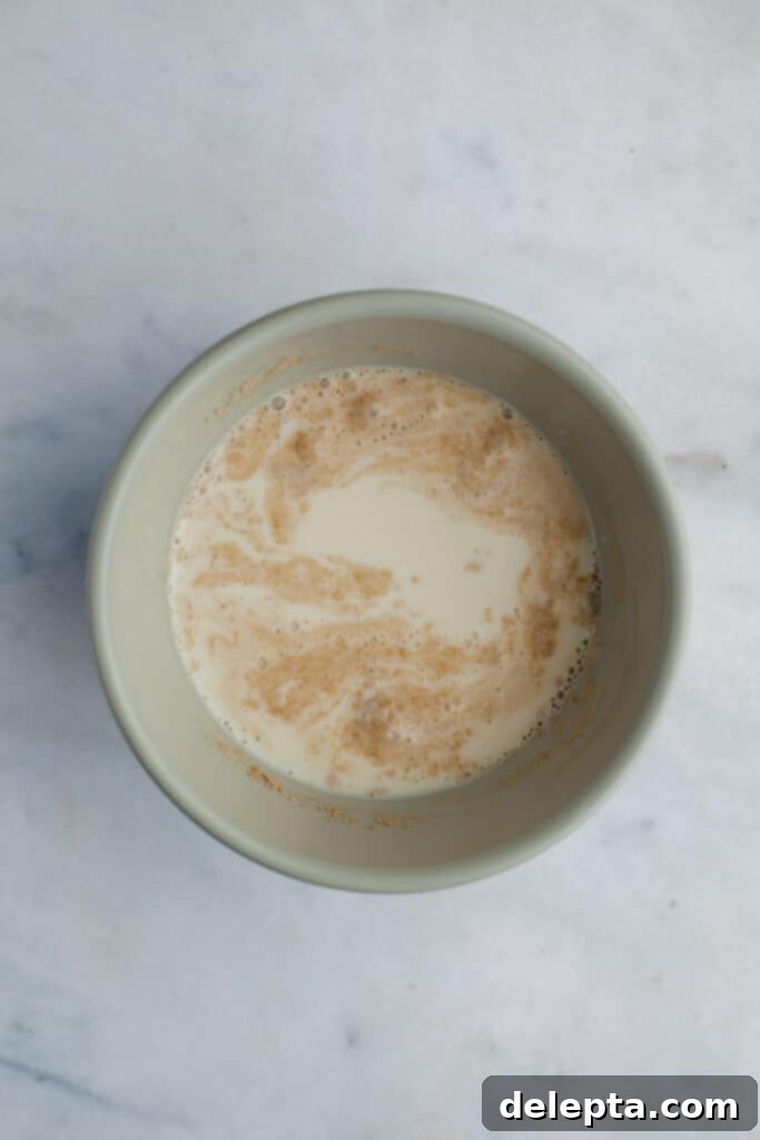 Pillowy Swedish Cinnamon Swirls 4 A small grey bowl with milk and active dry yeast mixed together, showing small bubbles on the surface, indicating the yeast is activating.
