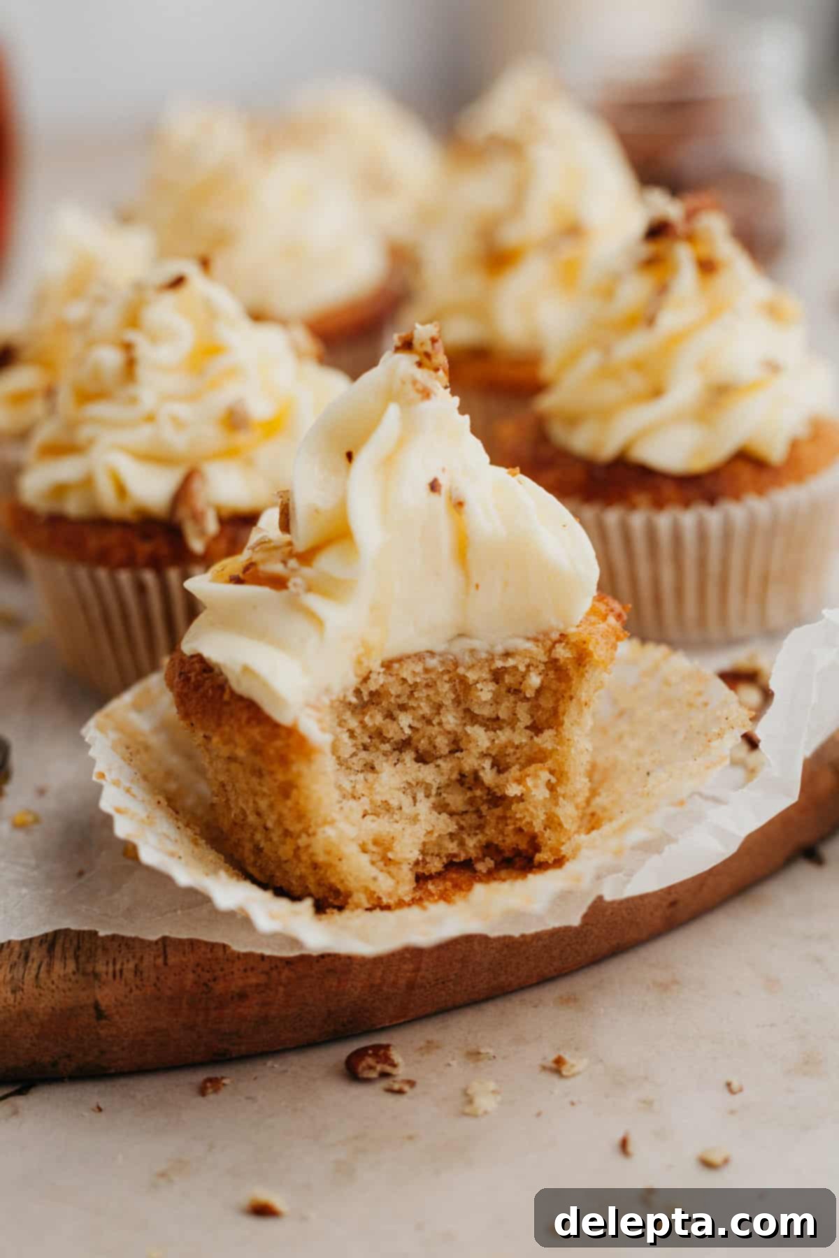 Golden Maple Delights 2 A close up of a maple cupcake with a bite taken out of it, showcasing the fluffy interior and creamy frosting