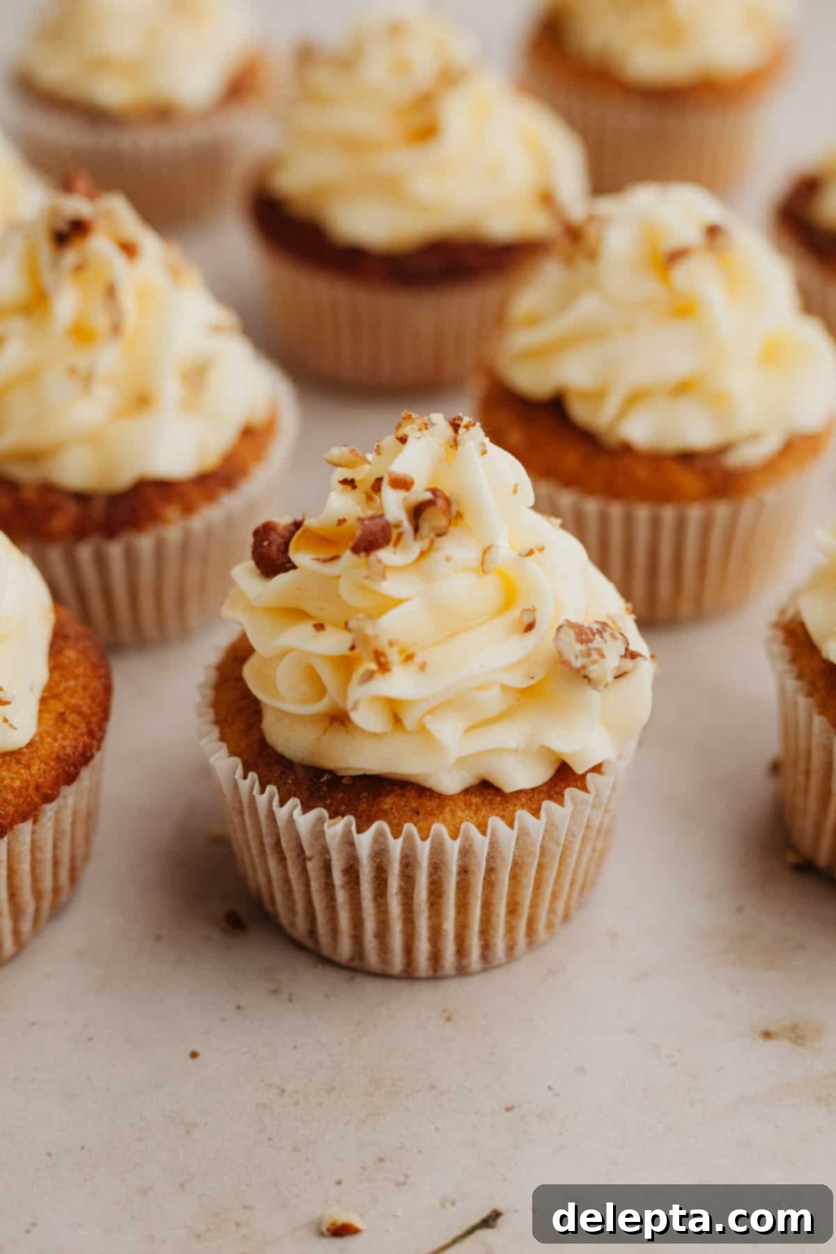 Golden Maple Delights 10 Several maple cupcakes with frosting on top, garnished with pecans and a maple syrup drizzle