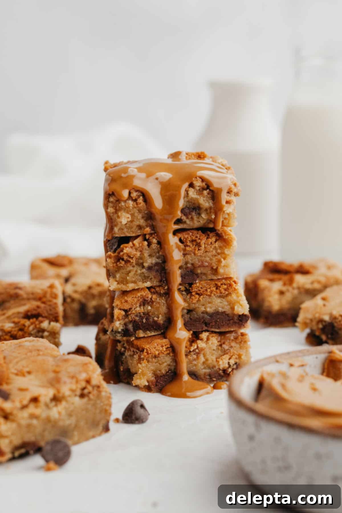 Easy One Bowl Brown Butter Biscoff Blondies 2 A tall stack of golden brown Biscoff blondies, with melted cookie butter oozing delightfully down the sides, resting on parchment paper.
